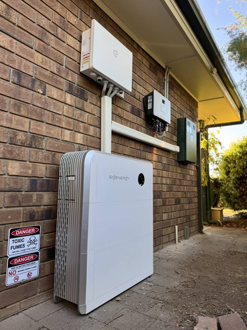 Sigenergy battery and inverter on a brick wall under the eaves